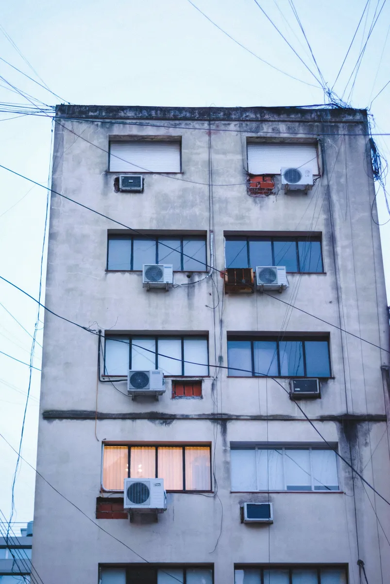 Apartment block facade with many split AC outdoor units fixed below windows