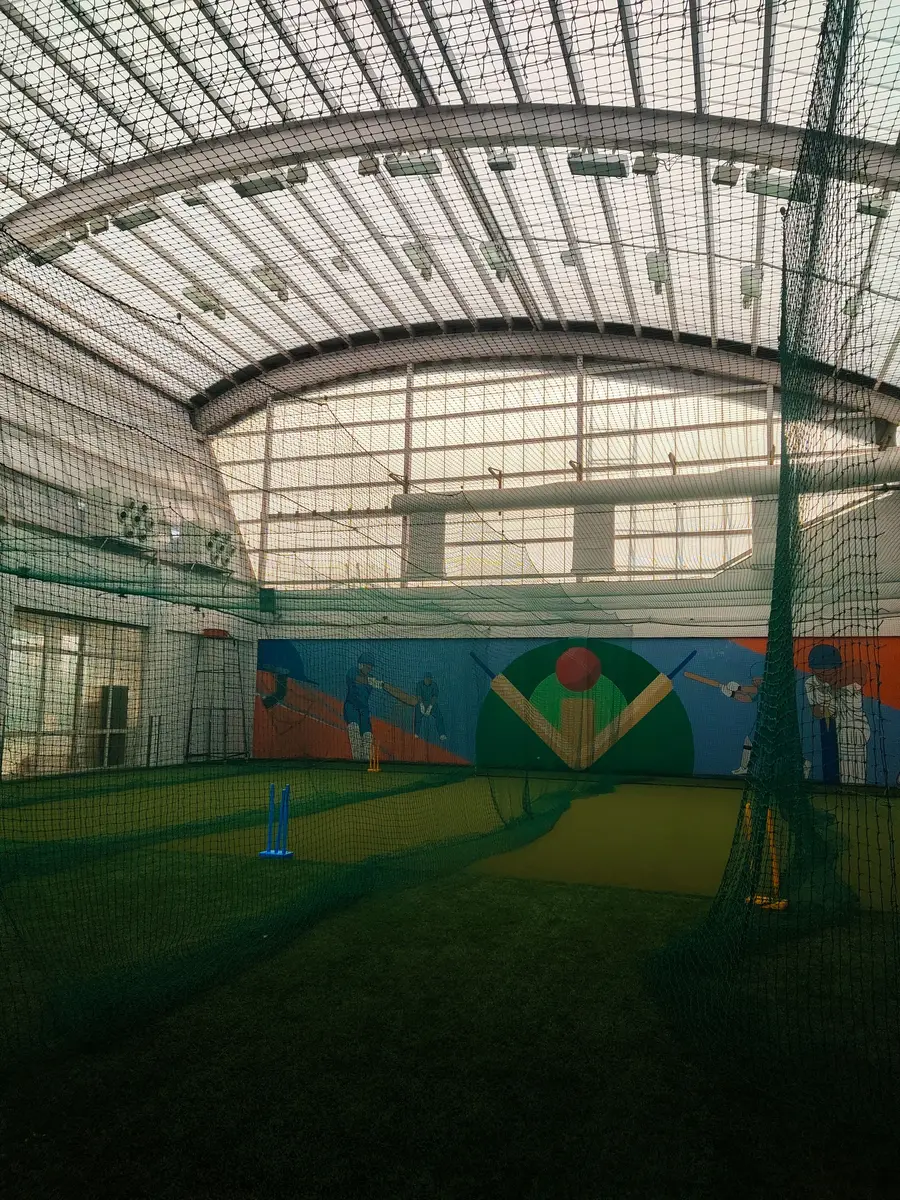 Indoor cricket hall with netted lanes and roof netting under a curved roof
